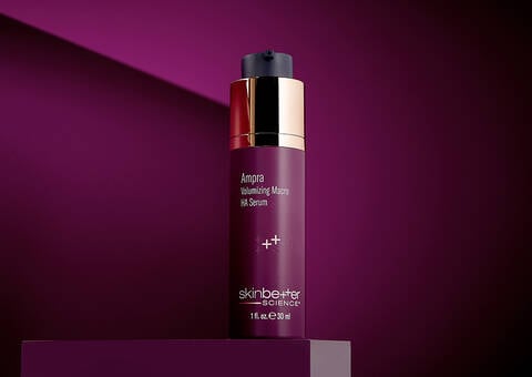 Grey background with table, women, and a product - AMPRA