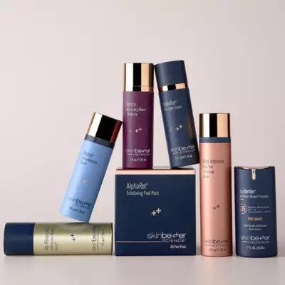 Four skinbetter science products—two tall pump bottles, one medium bottle with gold cap, and a small square jar—arranged on white and pale-blue geometric pedestals. A red 'National Rosacea Society Accepted' badge floats in the top left corner.